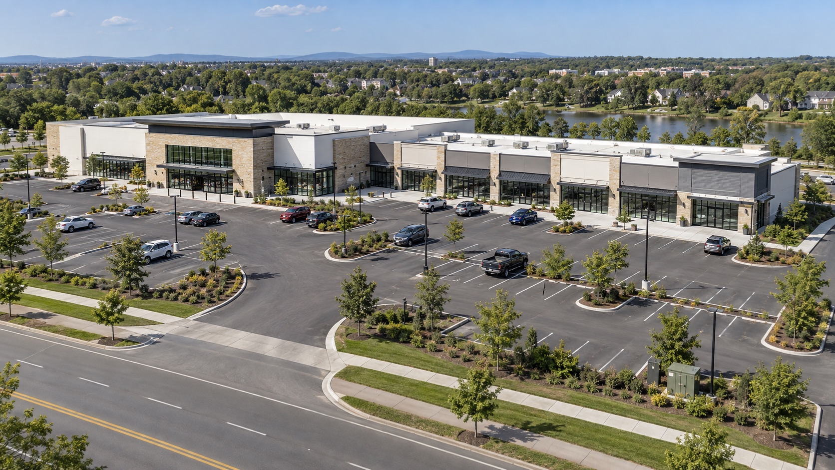 Oblique aerial view of a retail center with a large anchor storefront, shared parking and a driveway to the public street.
